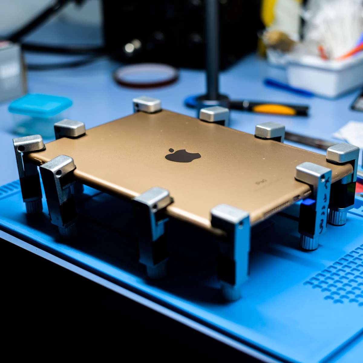 Apple device secured in a professional repair fixture on a workbench